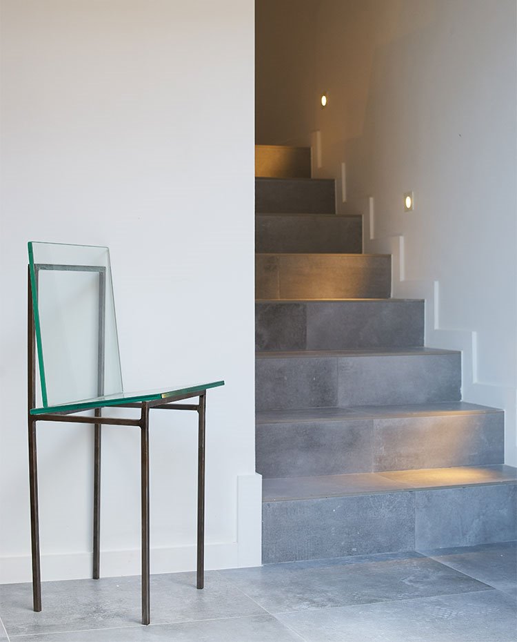 Silla de vidrio y acero junto a escaleras