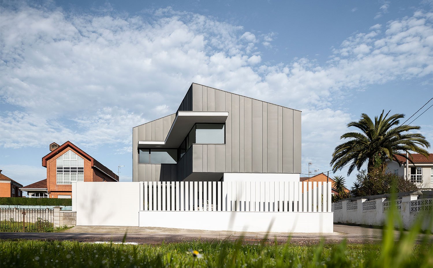 Vista general de vivienda desde calle con fachada sobresaliendo en tonos grisáceos
