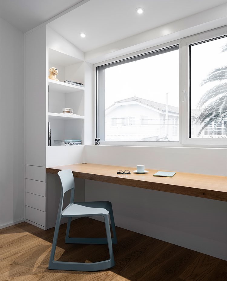 Zona de estudio junto a apertura al exterior con estructura de madera natural y blanco