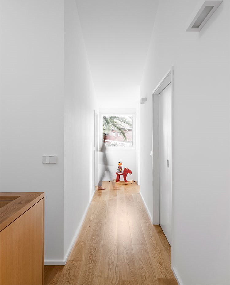 Zona de paso con suelo de madera y ventana cuadrada al fondo