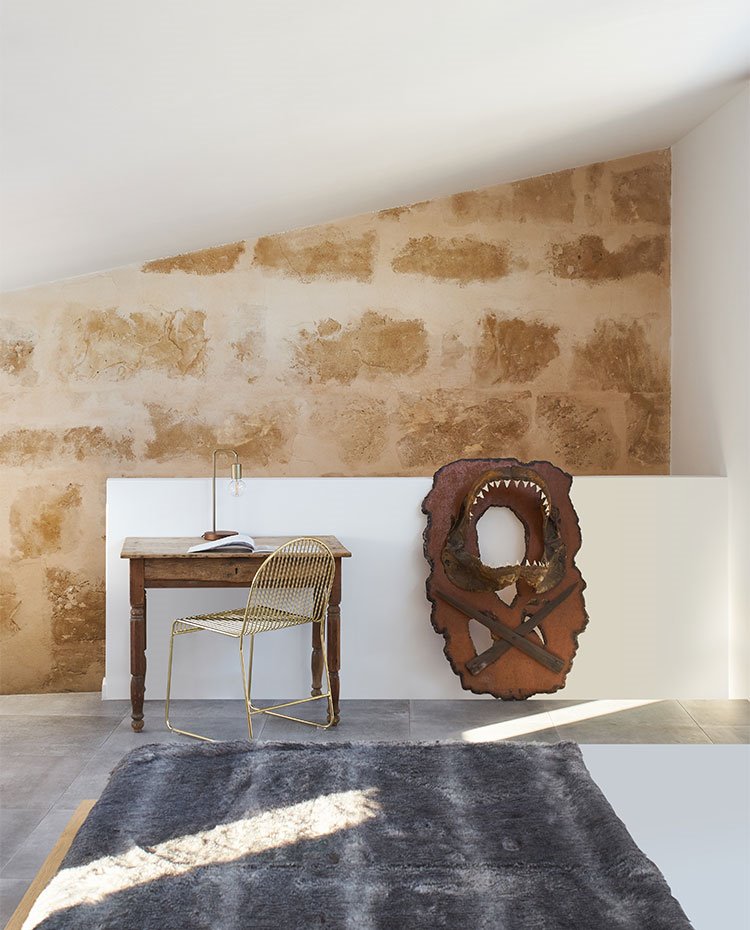 Zona de trabajo, mesa vintage, silla dorada, pared de piedra vista