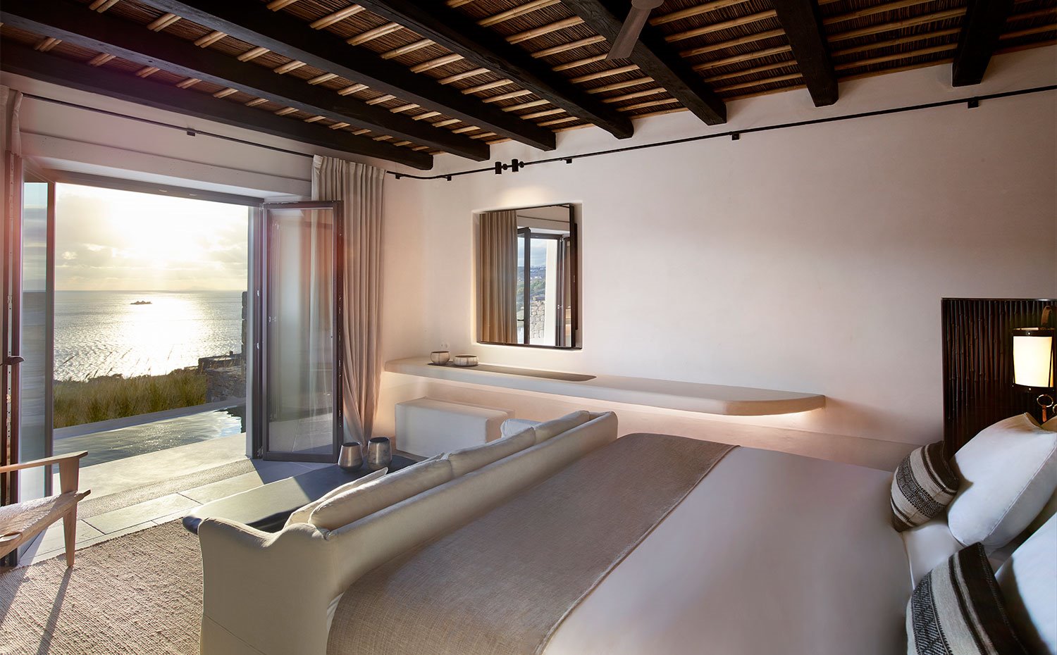 Dormitorio con amplia cama y cerramientos abiertos hacia piscina y mar