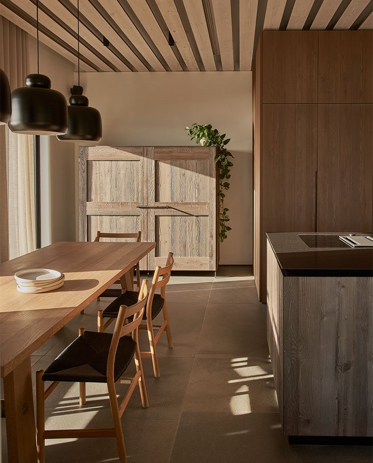 Cocina con isla y mobiliario con frentes de madera y mesa y sillas de madera