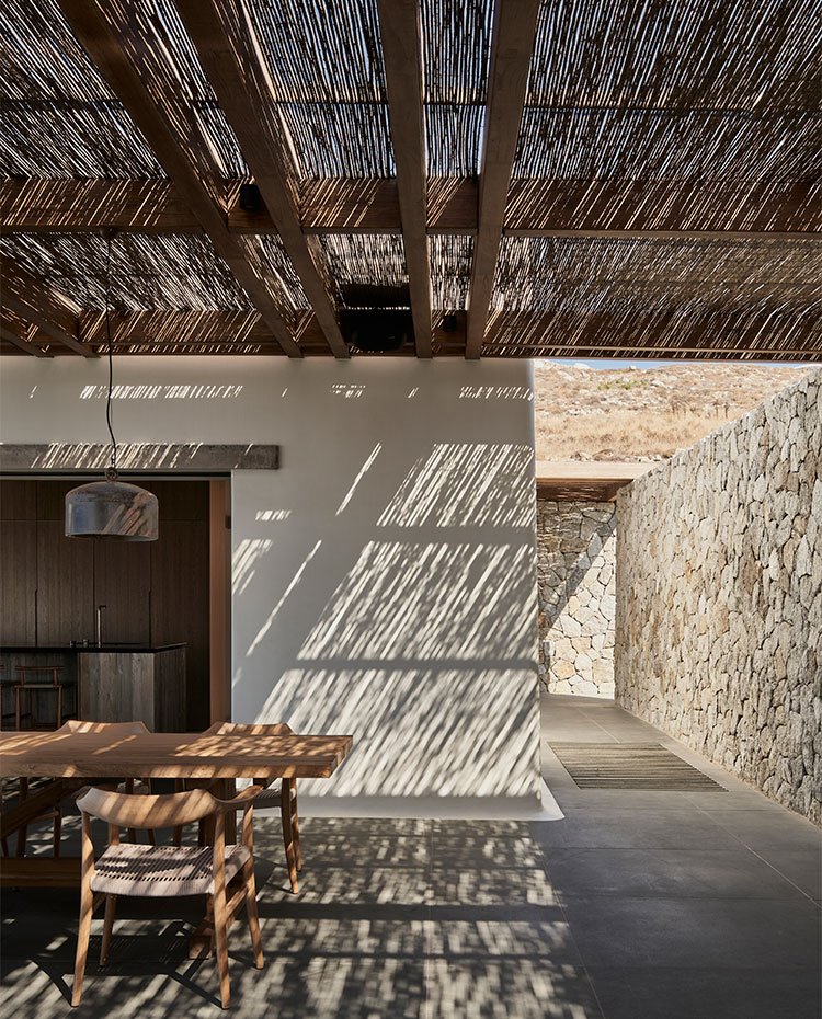 Comedor exterior junto a cocina bajo porche de madera y paja