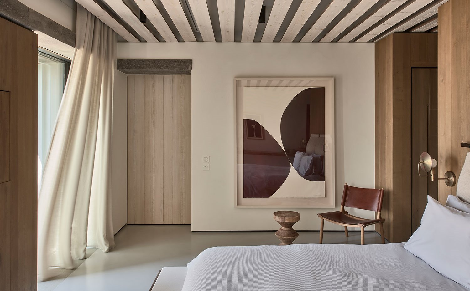 Cortisas de lino en los dormitorios con carpintería en acabado natural y silla con asiento y respaldo de piel