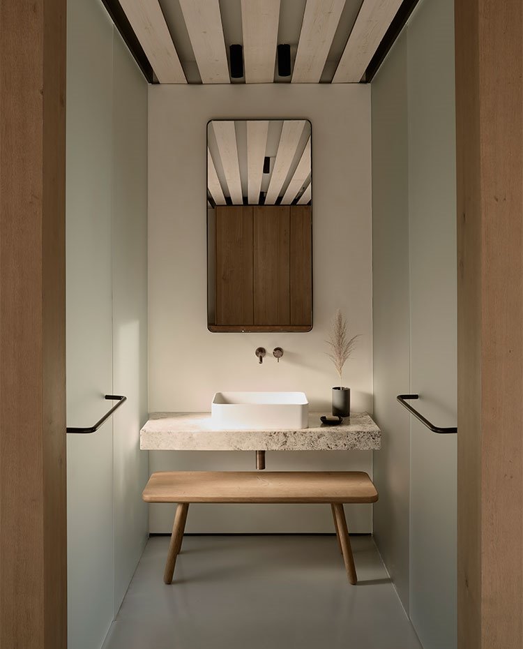 Cuarto de baño con zona de tocador central y cerramientos de cristal translúcido para la zona de ducha e inodoro