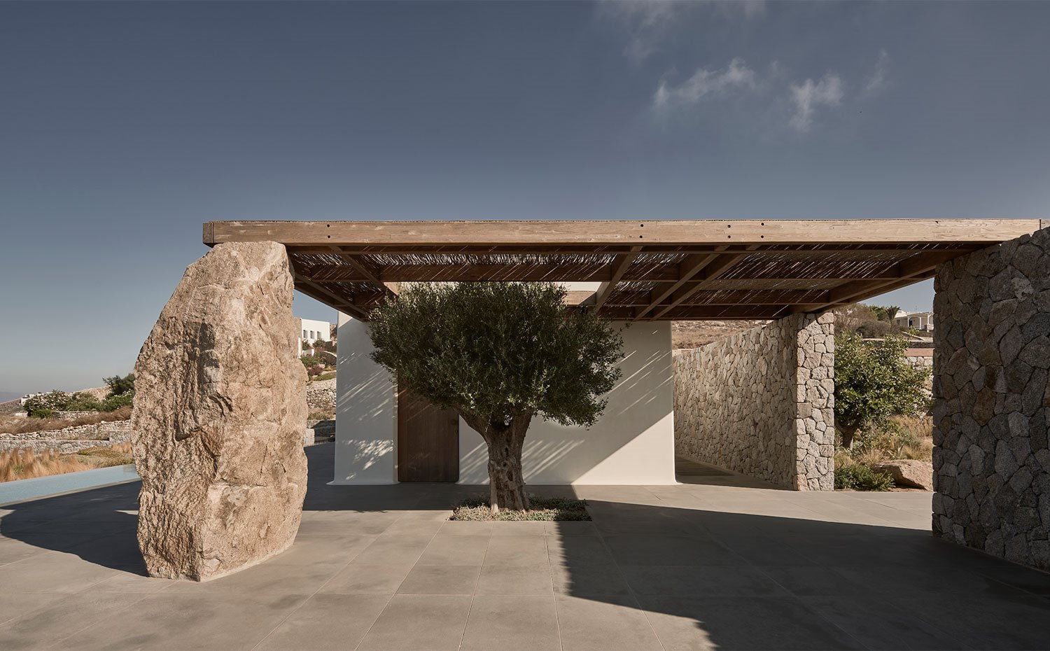 Porche con estructura de madera y ramas y apoyado sobre grandes rocas de piedra