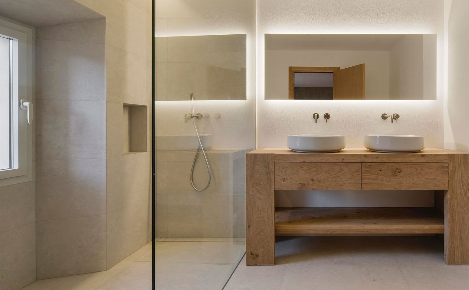 Cuarto de baño con zona de tocador de doble seno, mueble de madear, perfil de cristal para cerrar la ducha