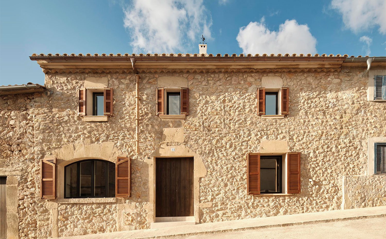 Fachada exterior de piedra desde calle con contraventanas de madera 