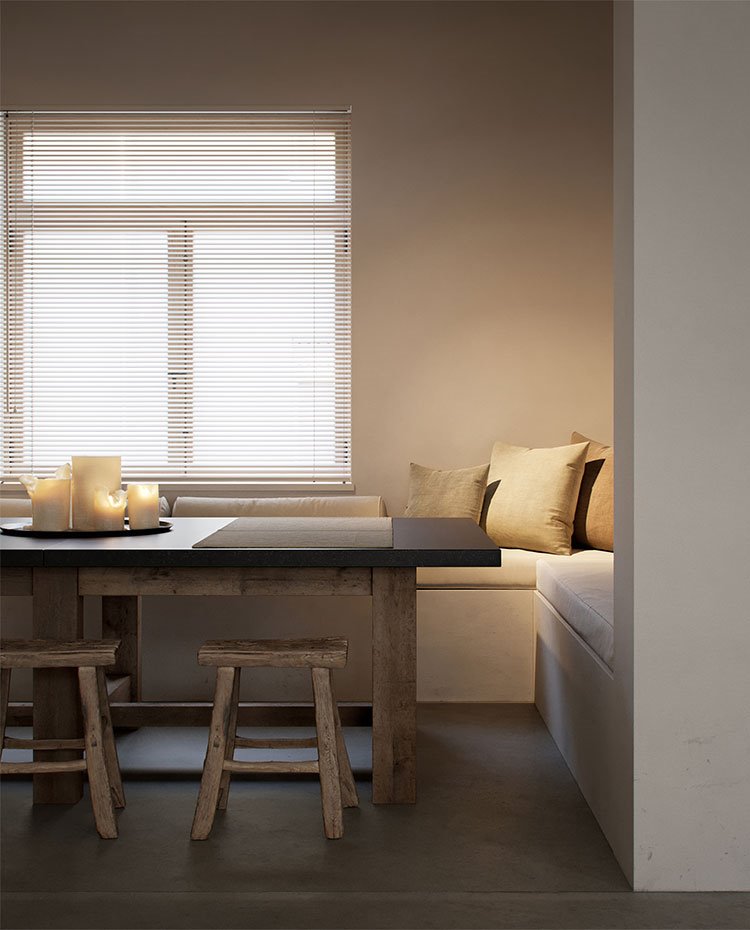 Mesa comedor con taburetes de madera, velas encendidas y banco de obra con cojines