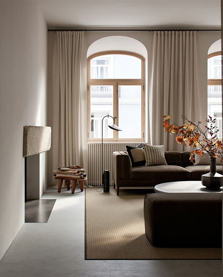 Salón con grandes ventanales, chimenea y sofás en color grisáceo