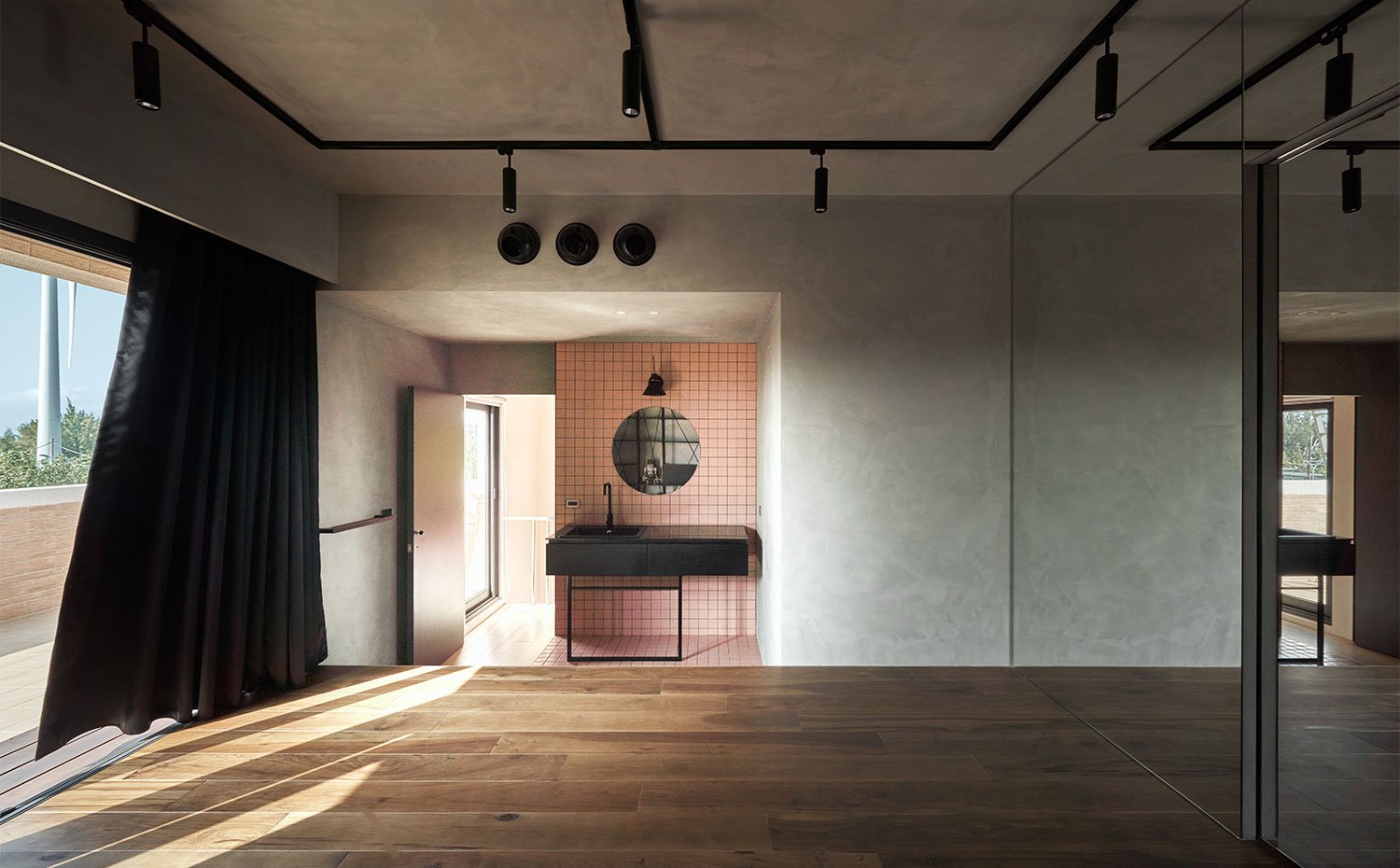 Amplia sala con suelo de madera, revestimiento en gris, tocador con pared revestida en rosa, mobiliario en negro