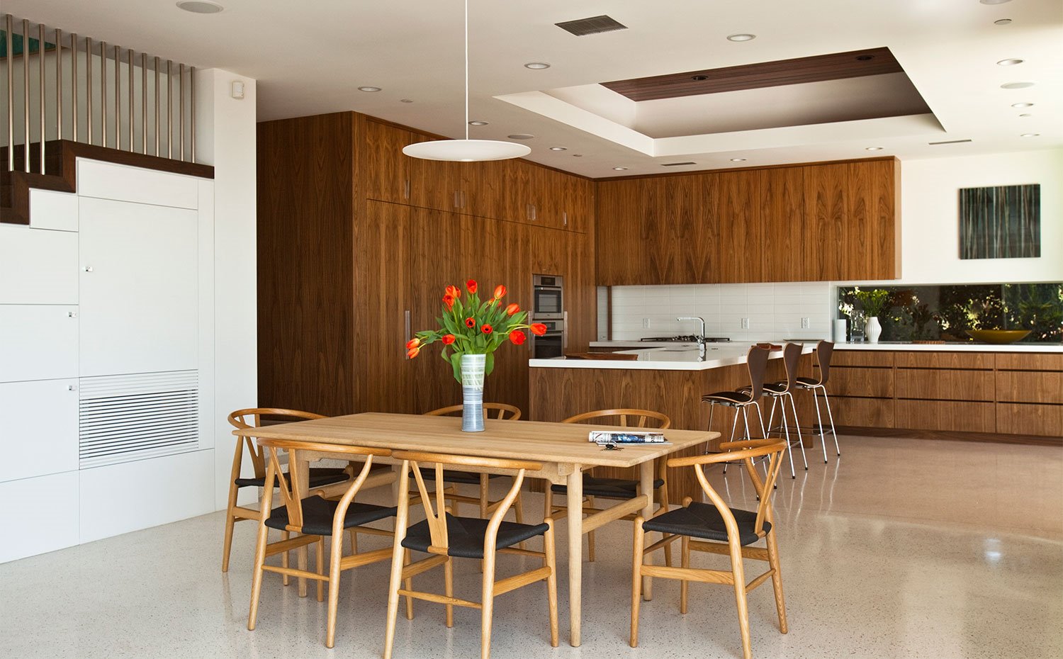 Cocina abierta con mobiliario de madera y mesa de comedor en madera natural con sillas a juego