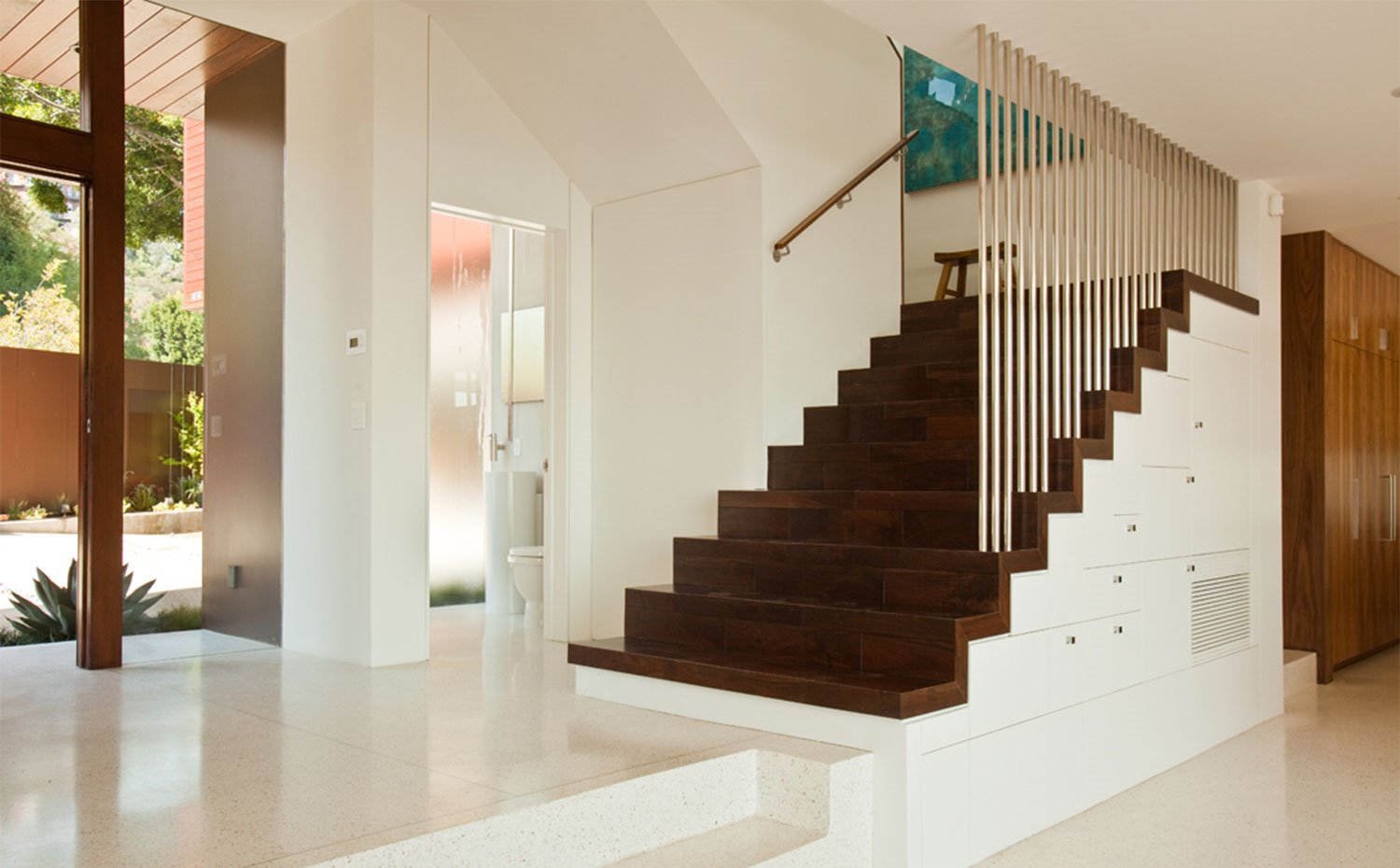 Escaleras revestidas de madera oscura en contraste con paredes en blanco