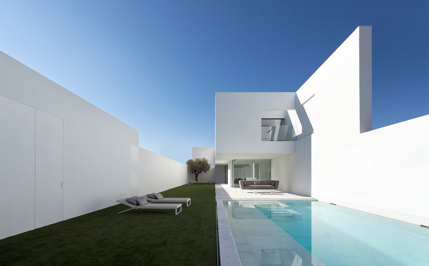 Exterior vivienda con tumbonas sobre cesped junto a piscina