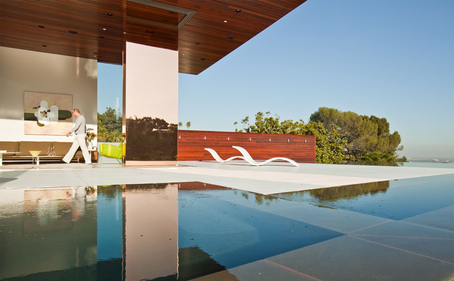 Salón abierto con columnas paneladas en acabado espejo, junto a piscina