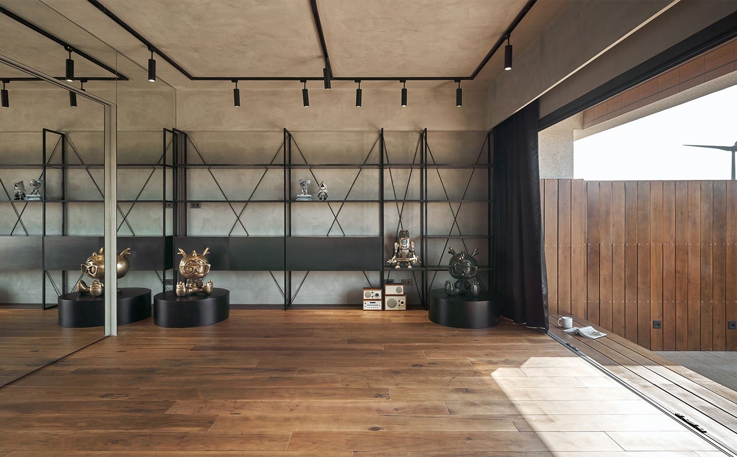 Salón con pared de espejos, suelo de madera, pared en gris y amplia estantería en negro