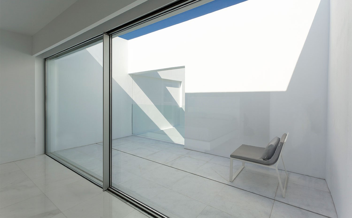 Terraza del nivel superior que asoma a la piscina a través del balcón con barandilla de cristal