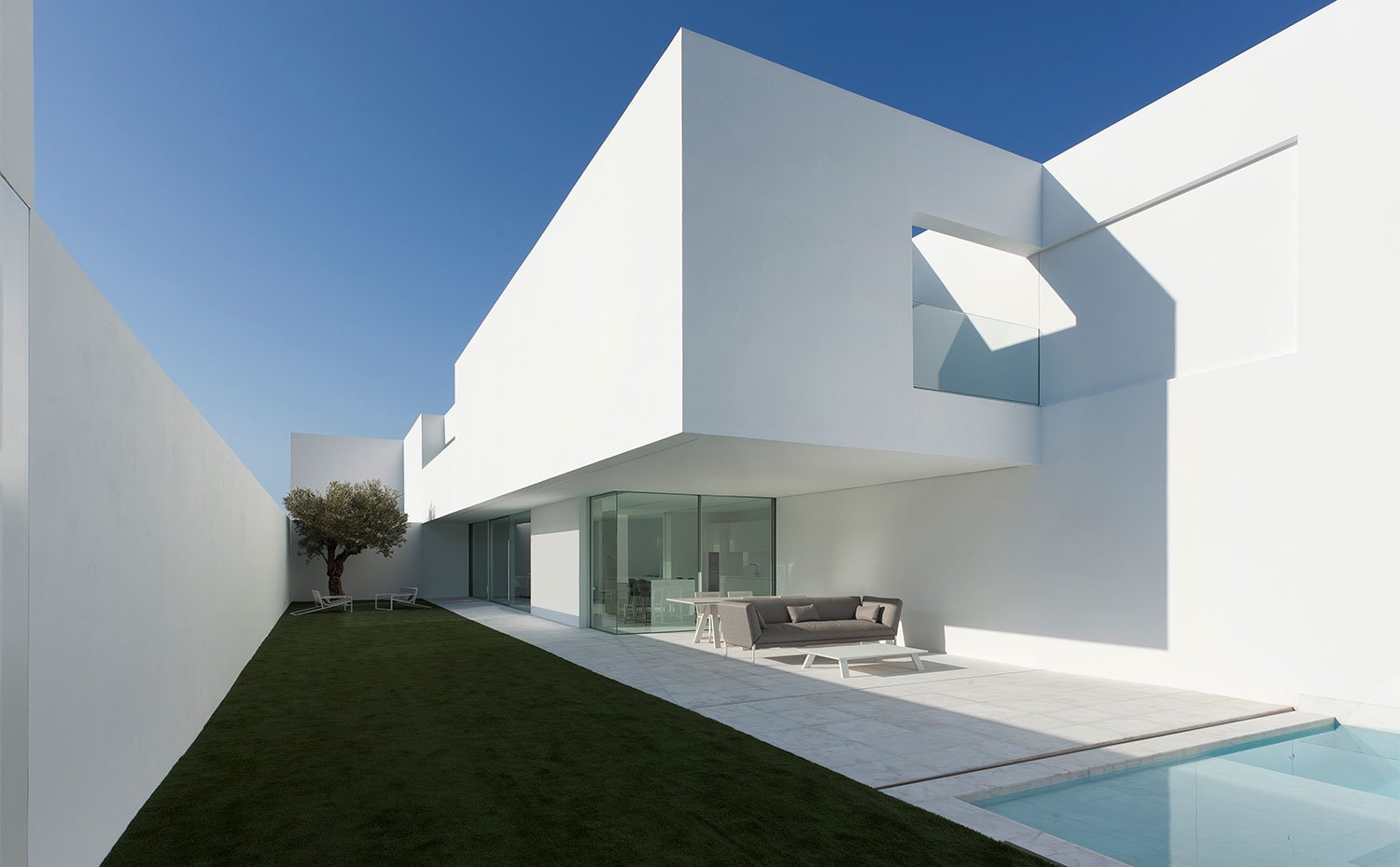 Terraza exterior bajo voladizo de nivel superior con sofá en gris