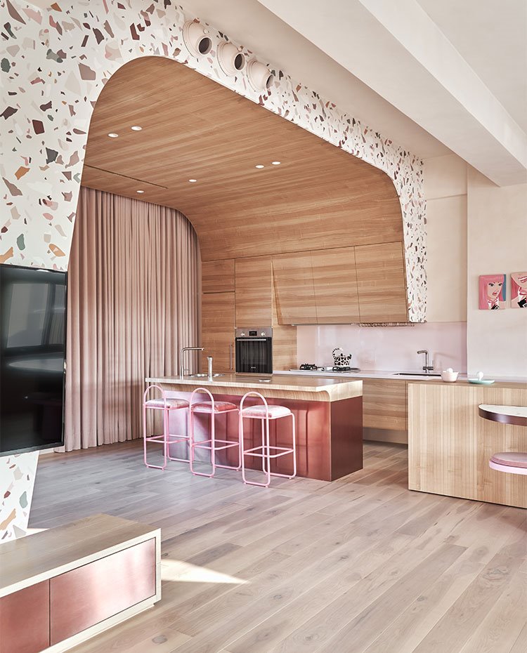 Zona de cocina con isla central bajo estructura revestida de madera y terrazo