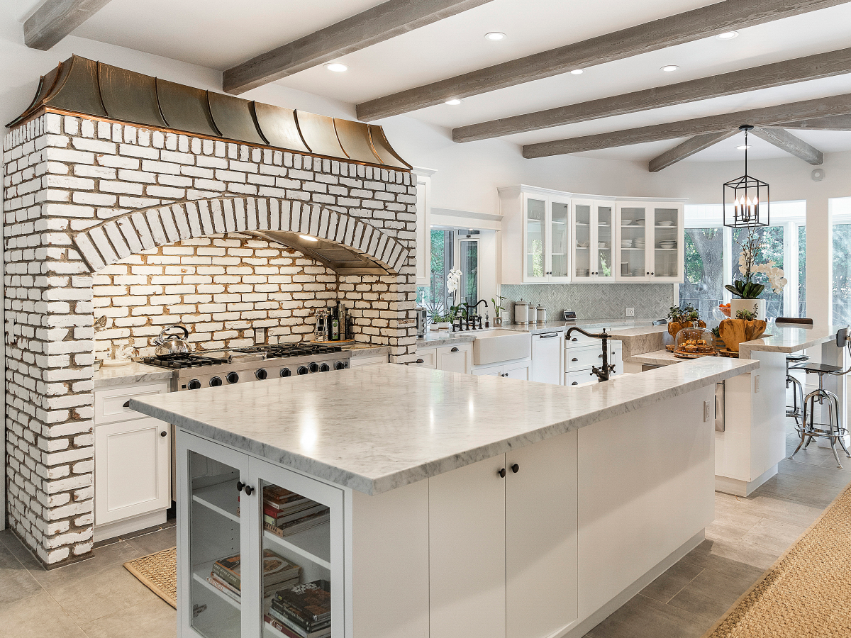 Casa Selena Gomez cocina con frontal de ladrillo y isla de marmol