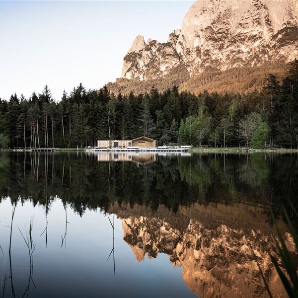 Una moderna cabaña de madera con lago, bosque y montaña