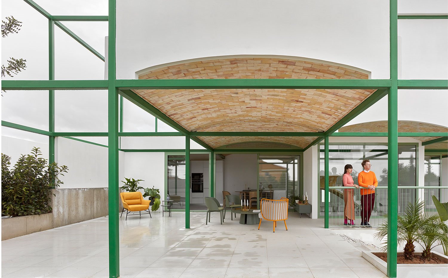 Exterior de terraza con suelo de baldosas grises en contraste con el color naranja y verde del mobiliario exterior