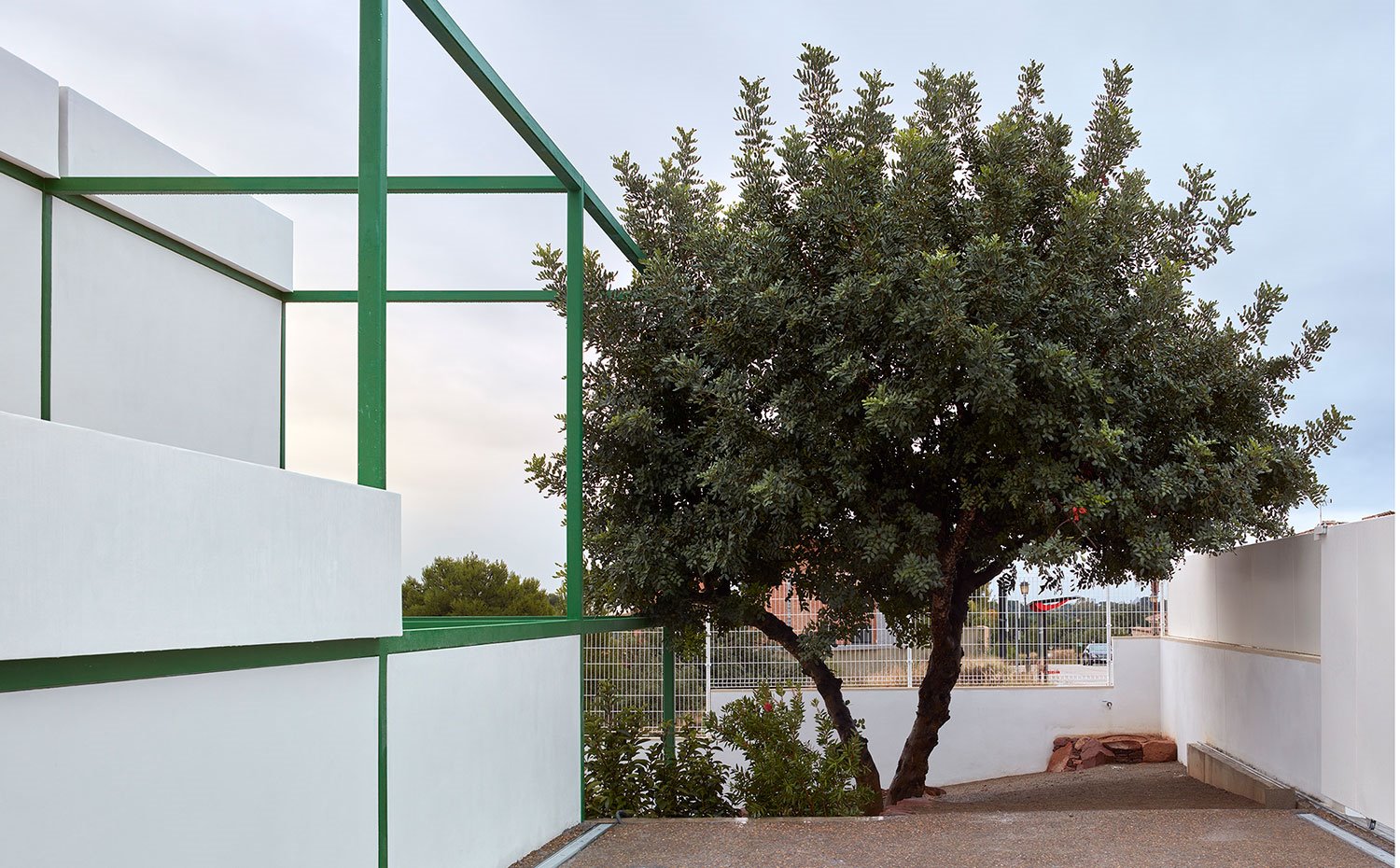 Lateral exterior de la vivienda con vegetación que rodea la vivienda y con parte de la estructura de fachada
