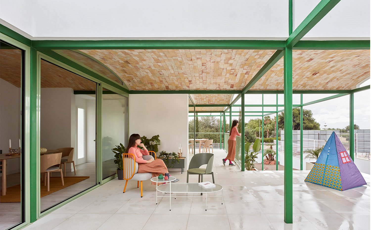 Terraza exterior con mobiliario en verdes y naranjas, cubierta con bóveda catalana