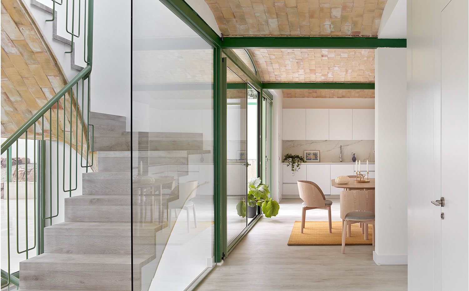 Zona de paso hacia la cocina con tabiquería de cristal que separa parcialmente la escalera