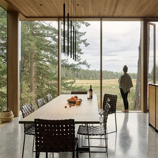 Amplia mesa de comedor de madera junto a la isla de trabajo de la cocina, techo recubierto de madera