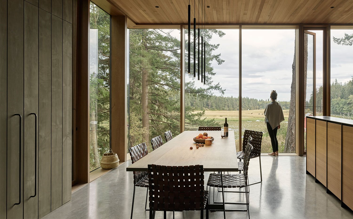 Amplia mesa de comedor de madera junto a la isla de trabajo de la cocina, techo recubierto de madera