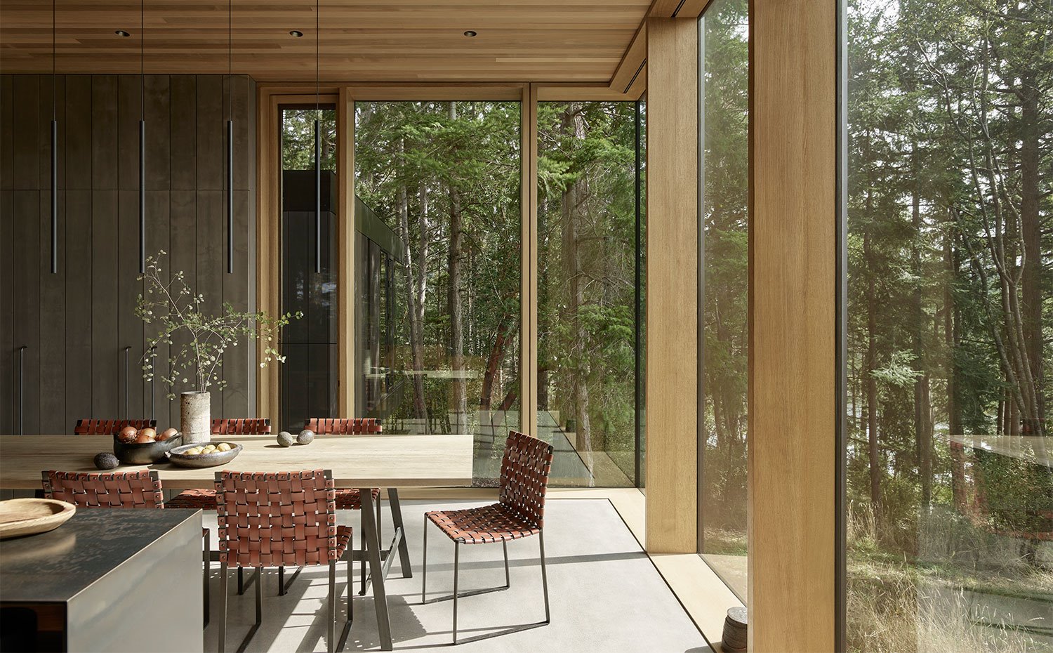 Comedor en extremo de sala abierta con mesa con encimera de madera y sillas en piel de estructura metálica