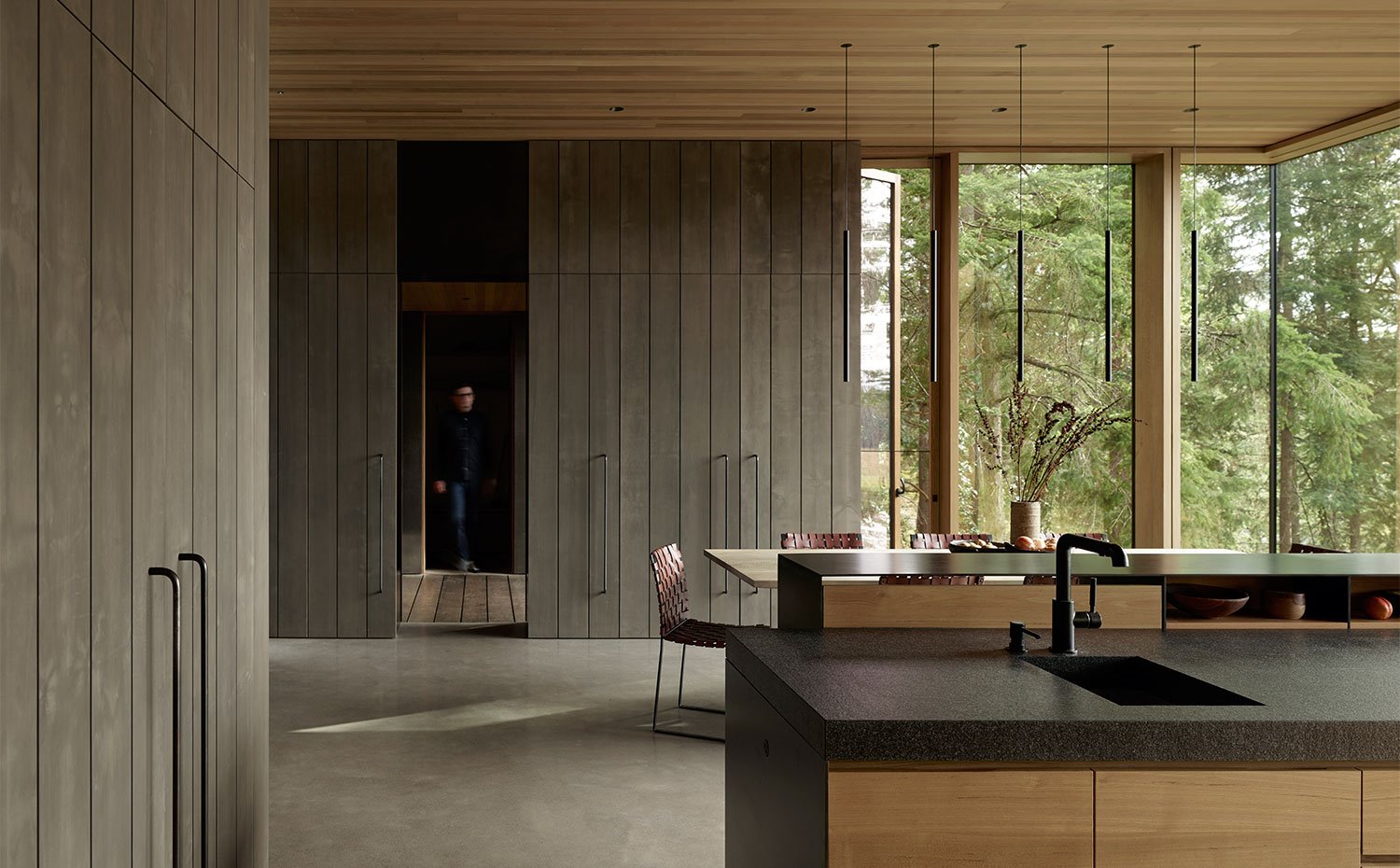 Doble isla de trabajo de cocina con mesa de comedor al fondo, armarios de almacenaje en madera