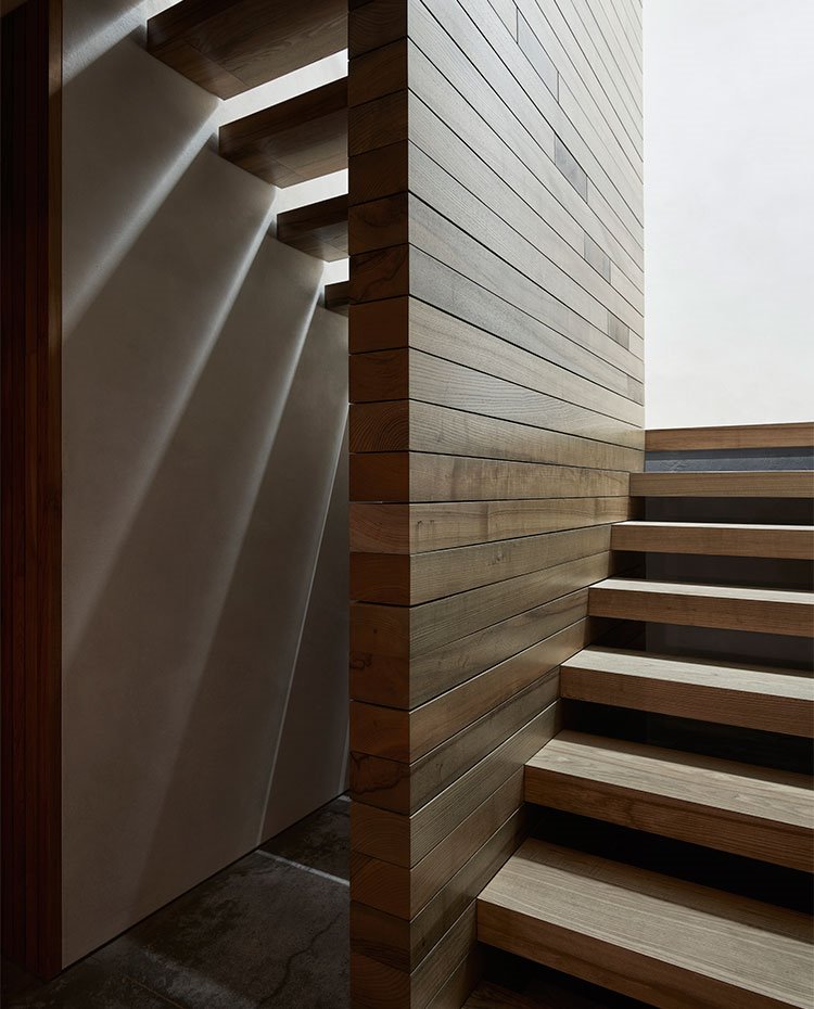Escaleras con tabiquería revestida de madera y peldaños de madera en voladizo