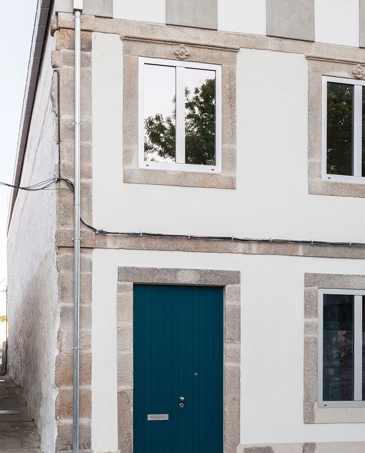FAchada exterior de vivienda en piedra, con puerta de madera pintada en azul cobalto