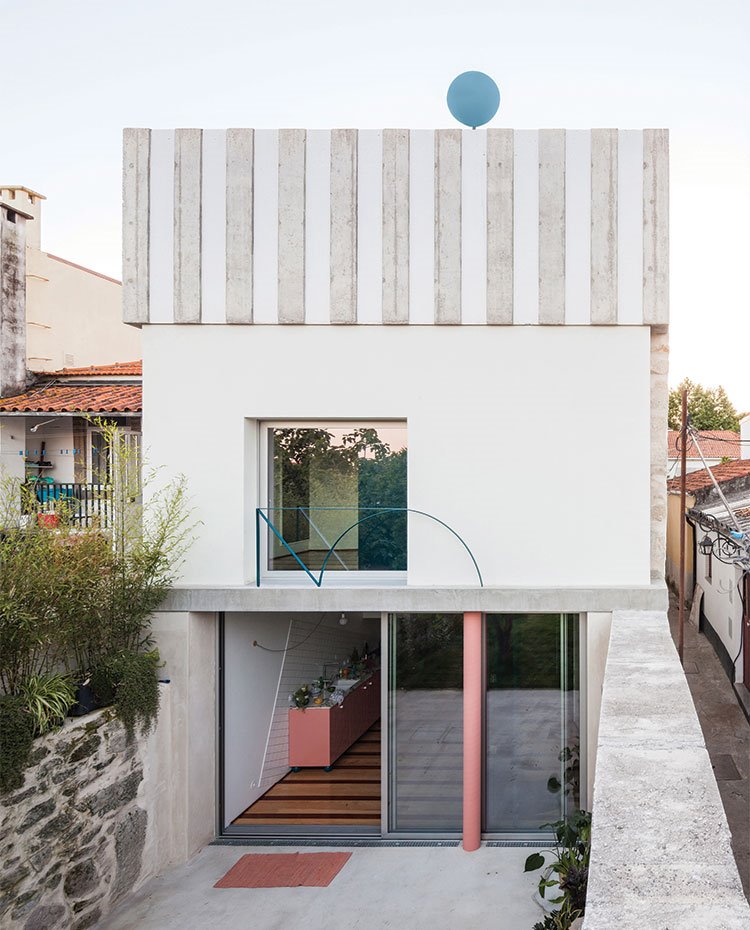 Fachada trasera de vivienda con aberturas en cristal y detalles de columna en rosa