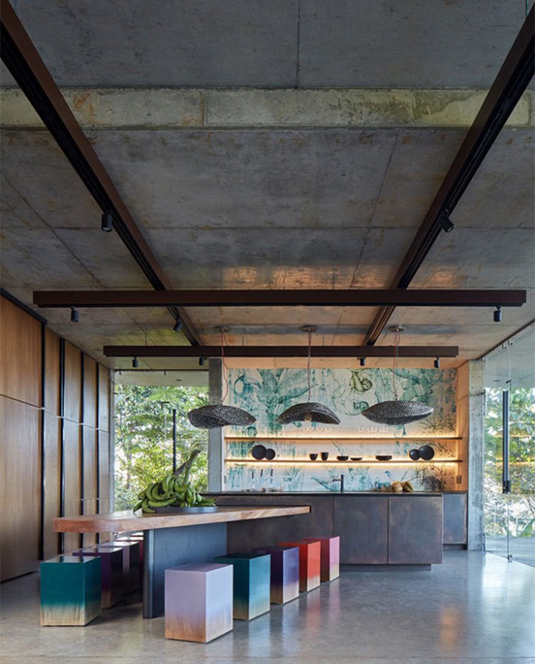 Comedor con mesa triangular y taburetes cúbicos de colores junto a cocina abierta con isla