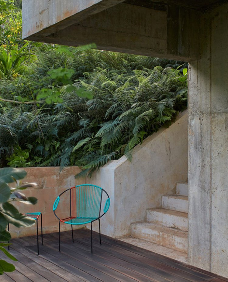 Escaleras y estructura de hormigón junto a suelo de lamas de madera y silla y taburete de colores