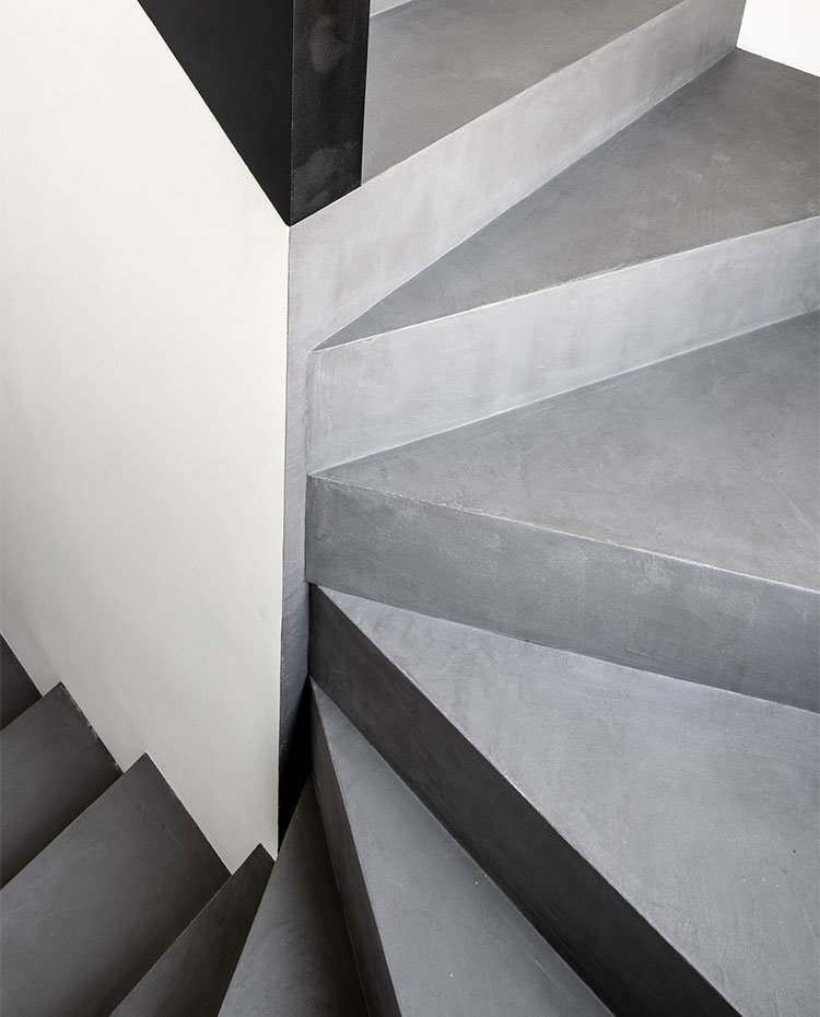 Escaleras pintadas en gris frente a detalles en negro y paredes en blanco