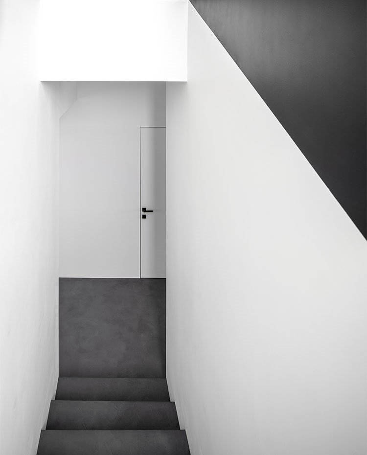 Hueco de escalera en negro en contraste con paredes y puertas en blanco
