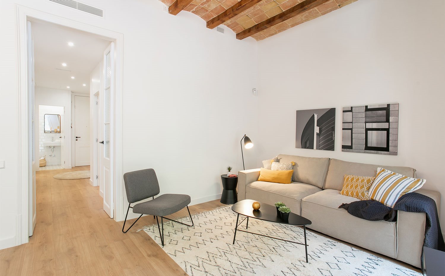 Salón con mobiliario en gris y negro, con cojines en amarillo