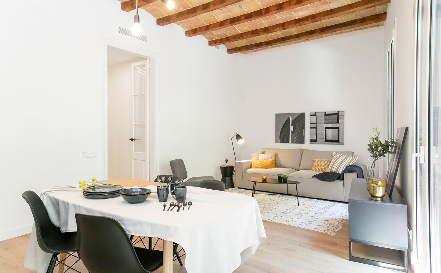 Vista desde cocina hacia comedor y salón con techo abovedado y vigas de madera