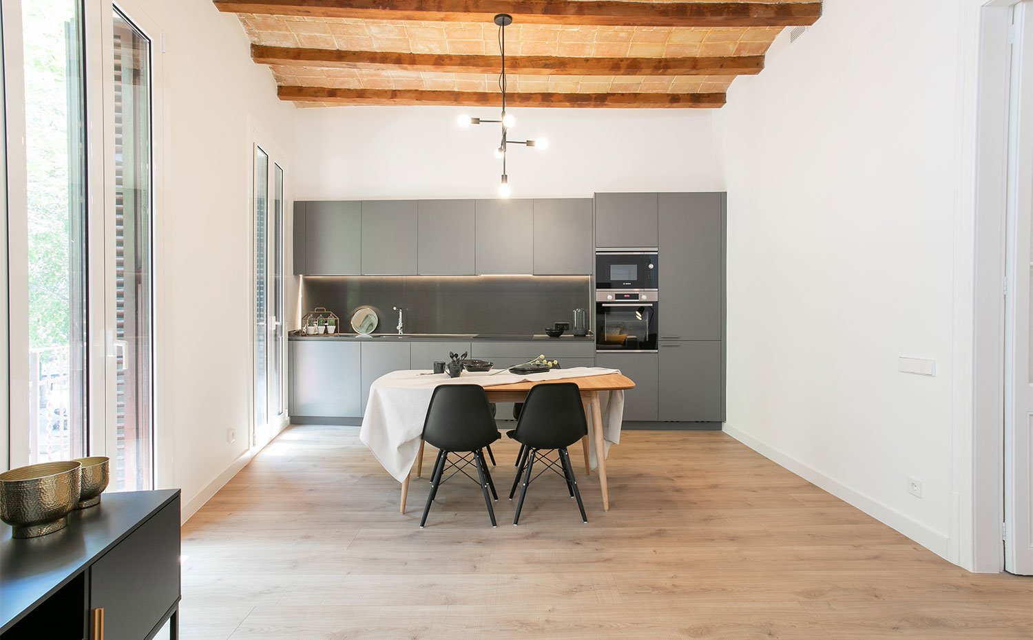 Vista frontal desde el salón hacia la cocina en gris con detalles metalizados 