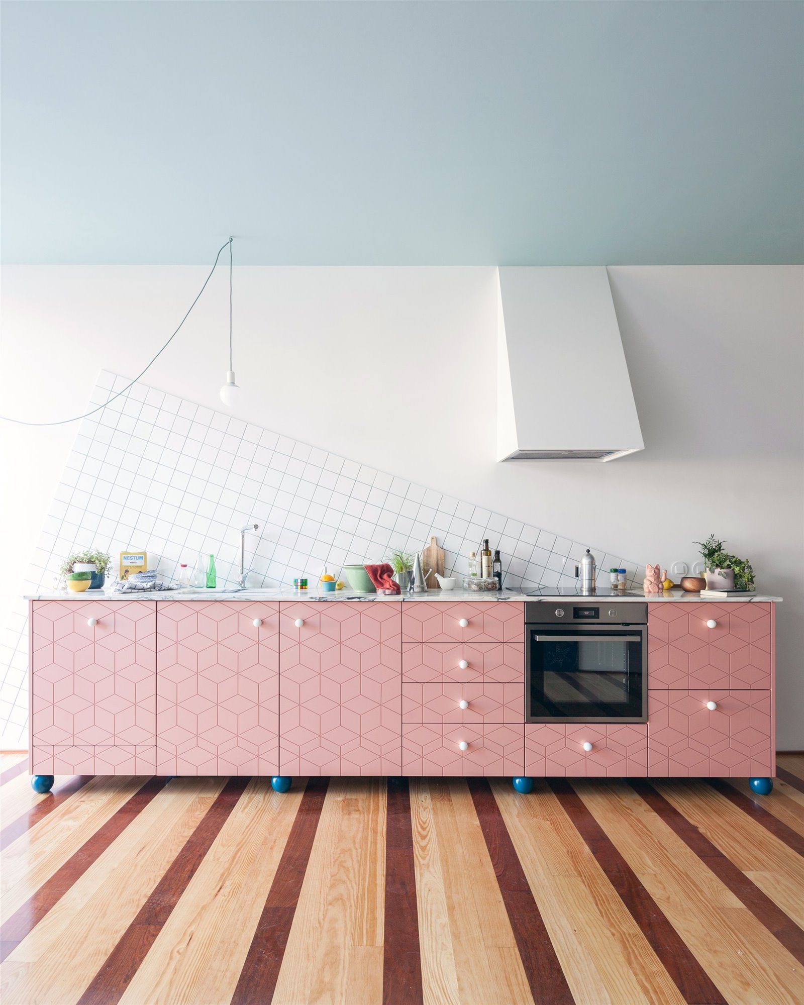 Mobiliario cocina en color rosa y tiradores blancos, suelo de madera con motivos de rayas