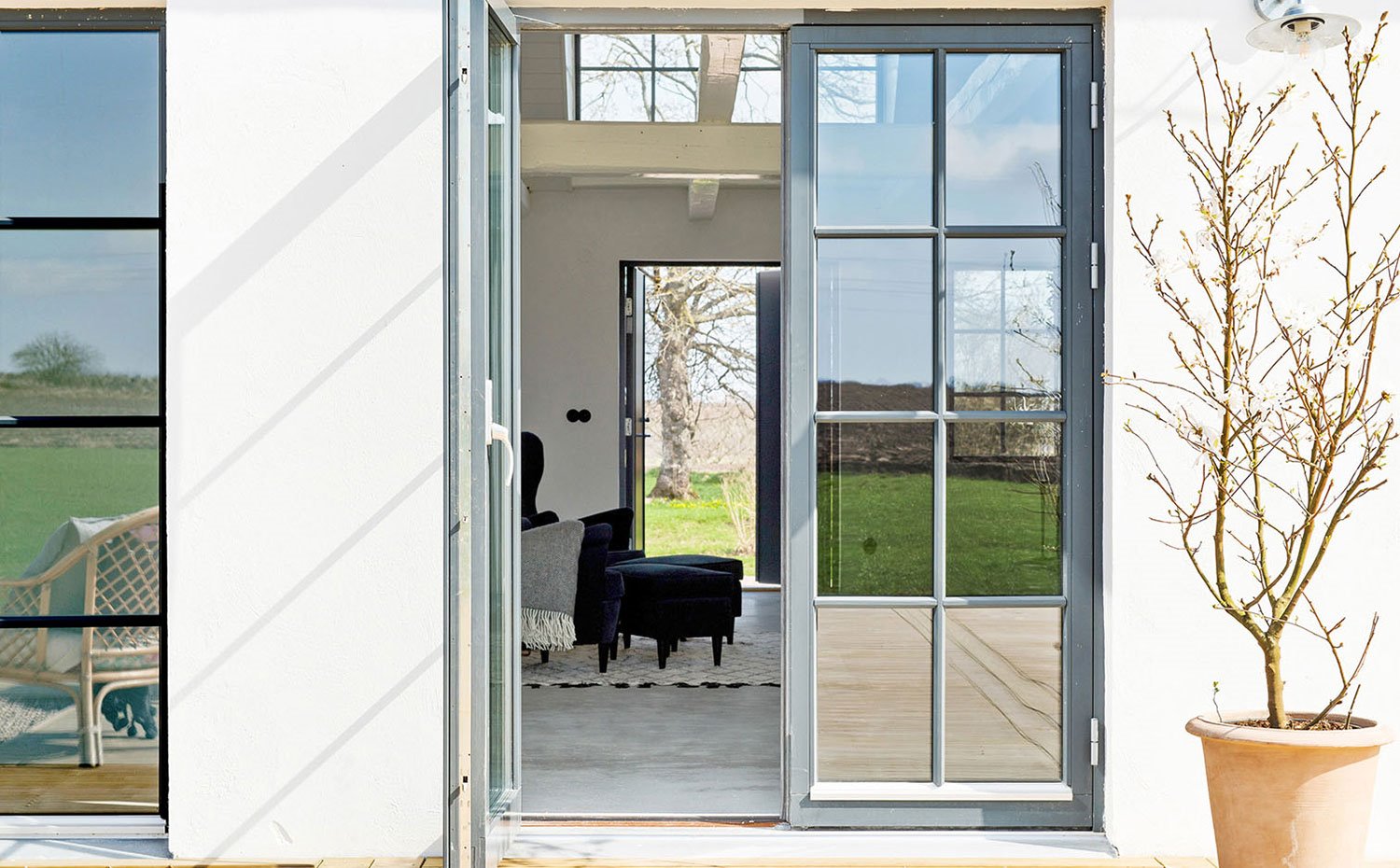 Acceso desde terraza al interior de la vivienda con puertas acristaladas con perfilería en tonos grisáceos