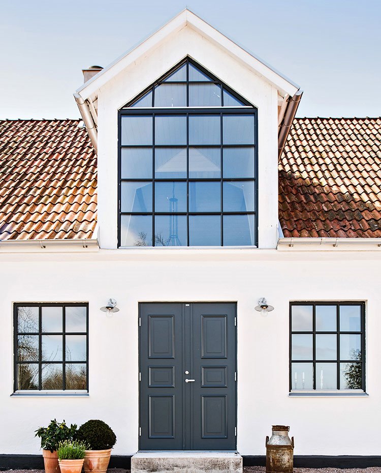 Puerta de acceso principal de vivienda con ventanas a ambos lados y amplia apertura superior