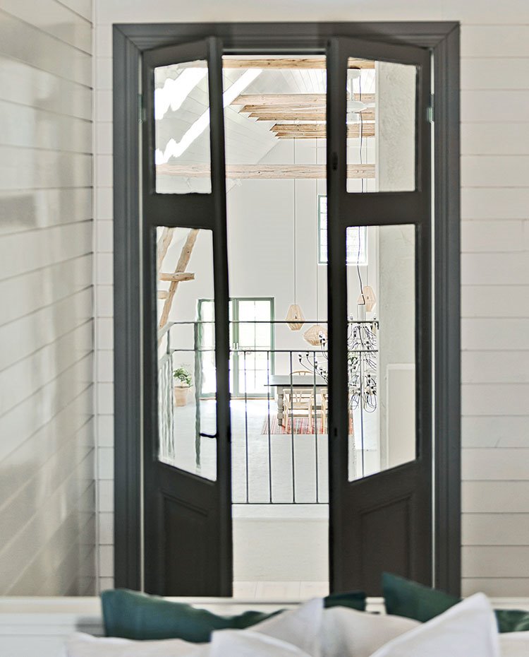 Puertas de cristal con perfilería en madera pintada de gris, revestimiento de madera en blanco