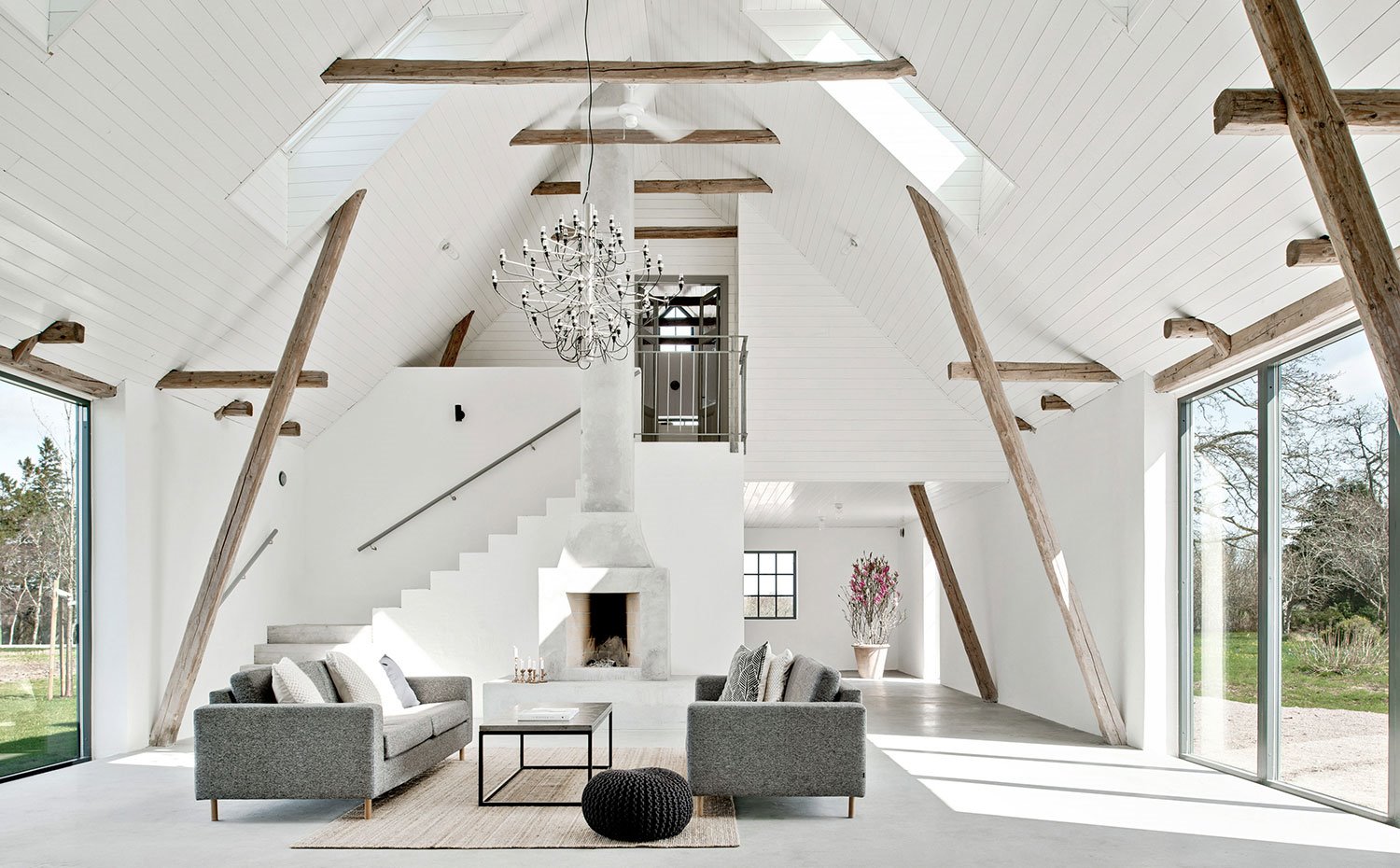 Vista salón con sofás en gris, techos de madera en blanco y vigas al natural