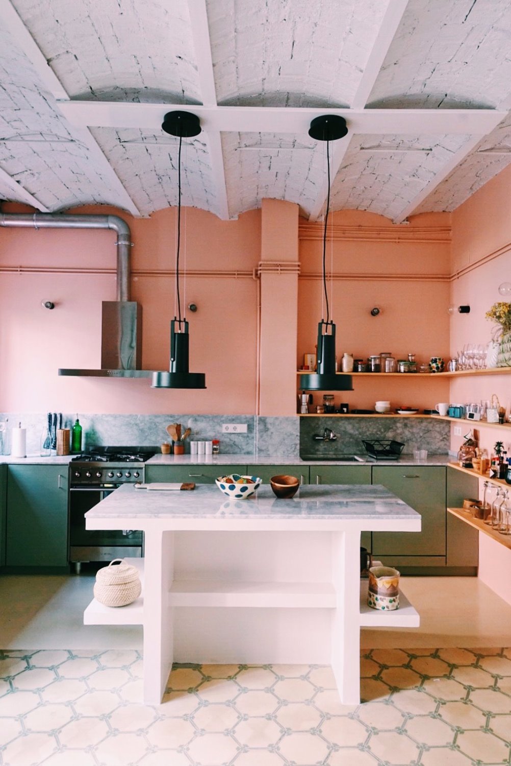 La cocina de Núria, donde la combinación del tono salmón en las paredes y el verde pastel en los muebles crea una atmósfera reposada.